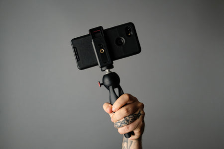 hand-holding-mobile-phone-and-tripod